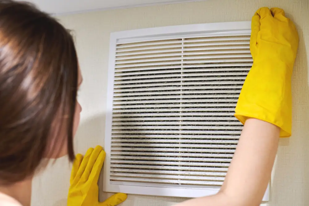 Cool Comfort Restored: How to Troubleshoot Common AC Problems - Woman checking the air filter of her AC.