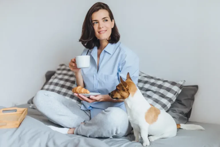 The Different Types of HVAC Filters and Which to Choose - Woman sitting on her bed. Small dog next to her.